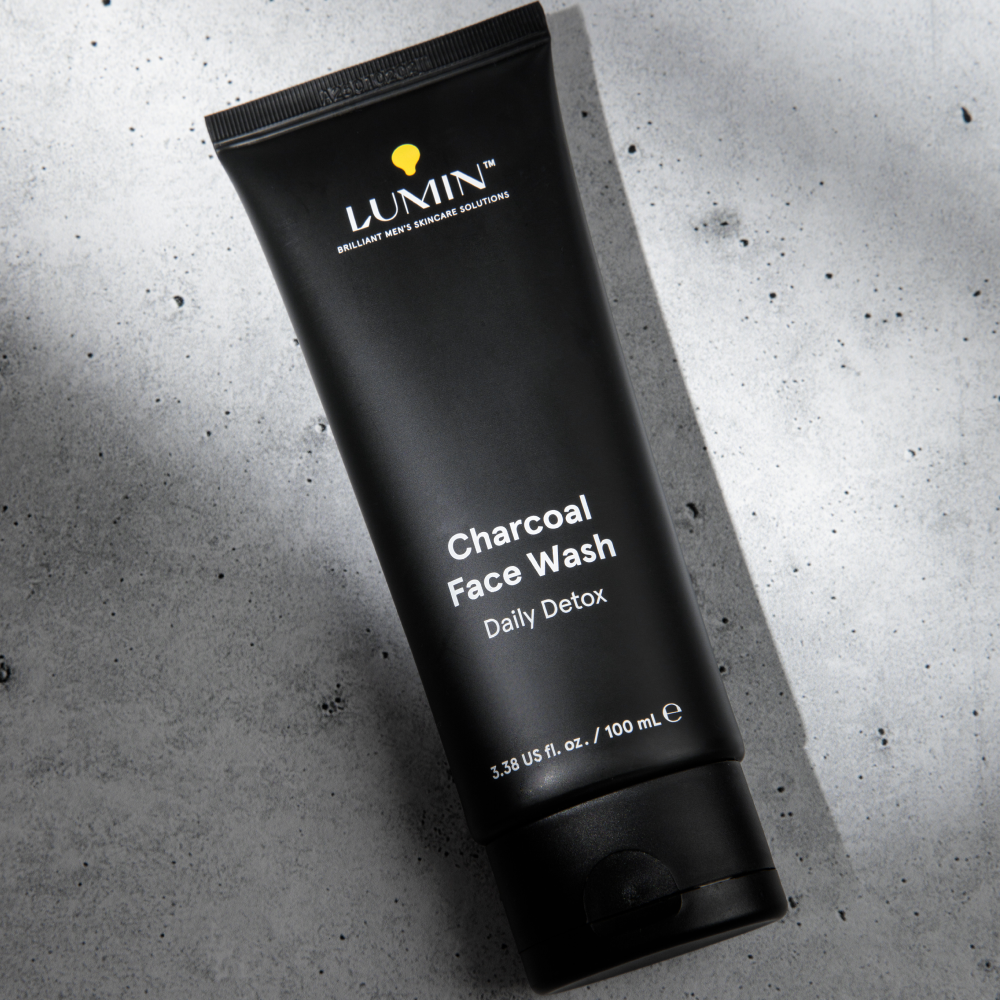 Lumin charcoal face wash tube for men's daily detox skincare on textured gray surface, 100ml packaging.