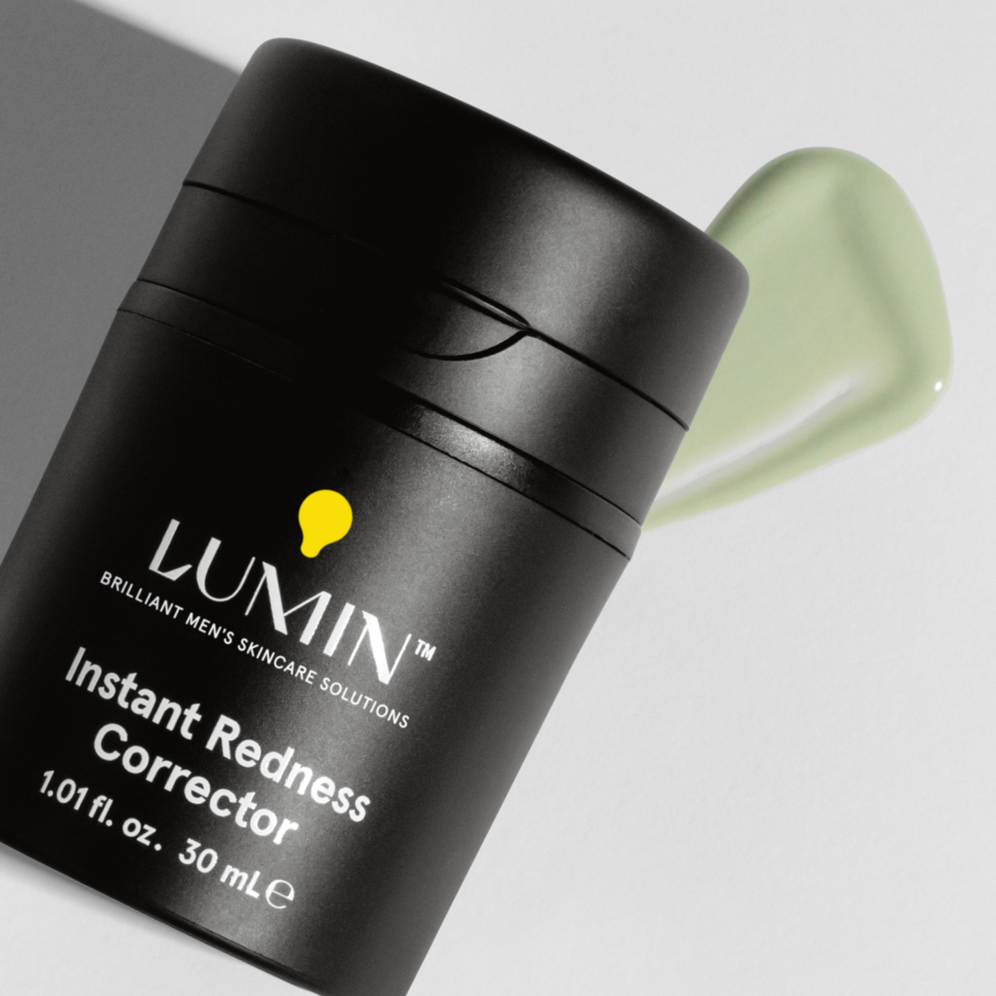 Lumin Instant Redness Corrector men's skincare cream in black bottle with green soothing gel on white background
