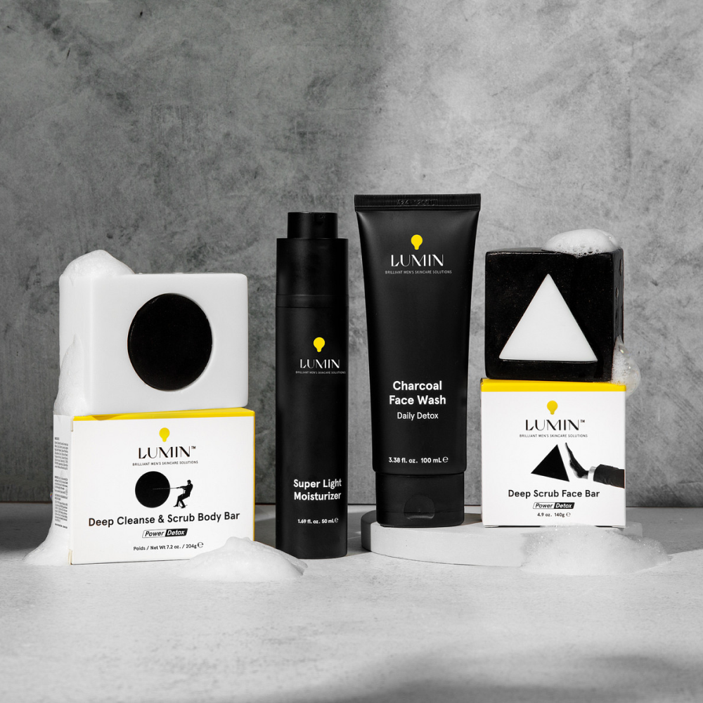 Lumin men's skincare products including Deep Cleanse & Scrub Body Bar, Super Light Moisturizer, Charcoal Face Wash, and Deep Scrub Face Bar with foam.